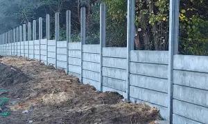 Wykończenie słupów zewnętrznych w postaci betonowego muru oporowego, budowanego z prefabrykowanych elementów, z widocznym terenem budowy.