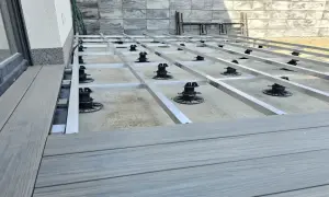 Budowa tarasu z deski kompozytowej. Widoczna konstrukcja nośna z aluminiowych profili na regulowanych podporach.